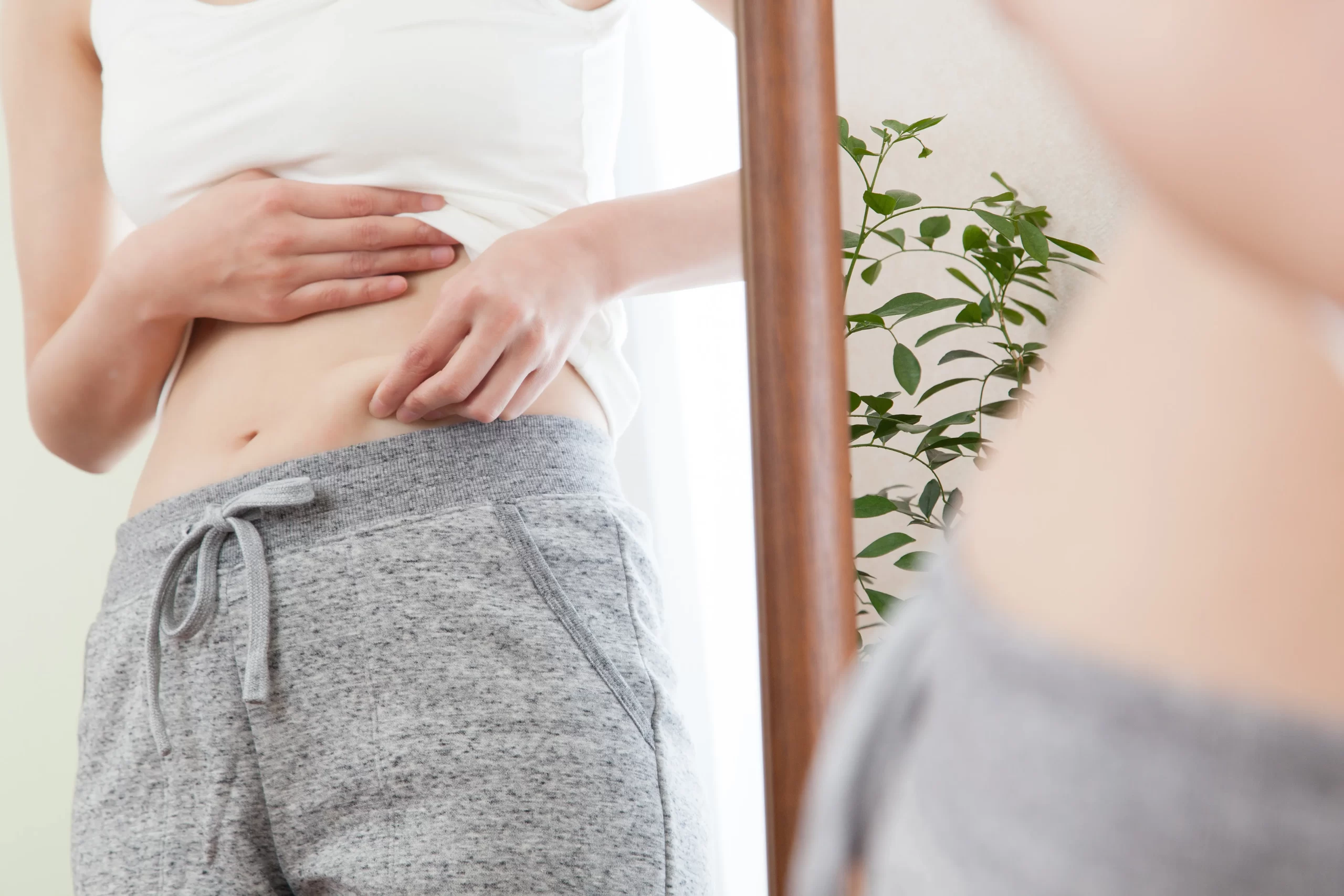 鏡の前でお腹まわりの変化を確認する40代女性