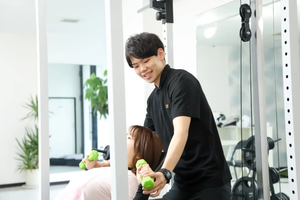 パーソナルジムでトレーナーがマンツーマンでトレーニングをサポートしている様子