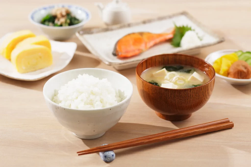 ご飯、味噌汁、焼き魚などが並んだ和食の朝食。栄養バランスを意識した健康的な食事の一例。